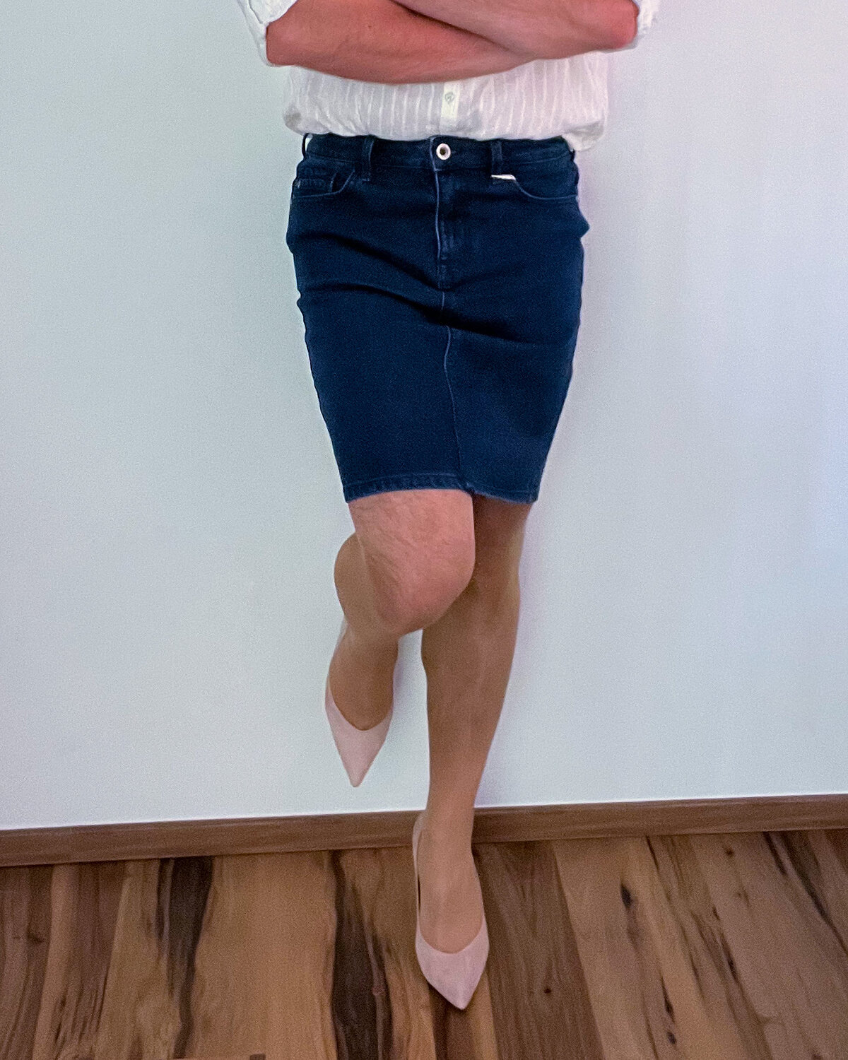 Crossed leg in a denim skirt with a nude pump and a slim heel
